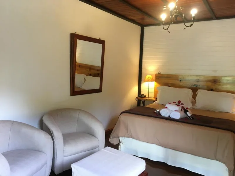 Quarto com cama e poltronas no Chalé 01